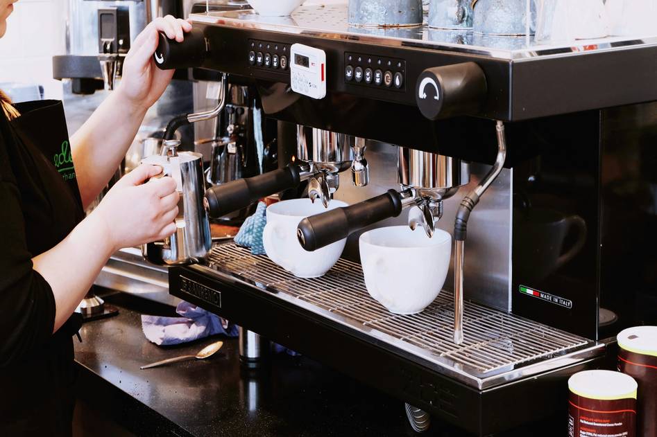 Modern smart coffee maker on kitchen counter with steam and beans